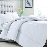 White Cosy Home Anti-Allergy Hollowfibre Quilt shown fitted on a bed with white pillows, grey upholstered headboard, and channel-stitched baffle box design.