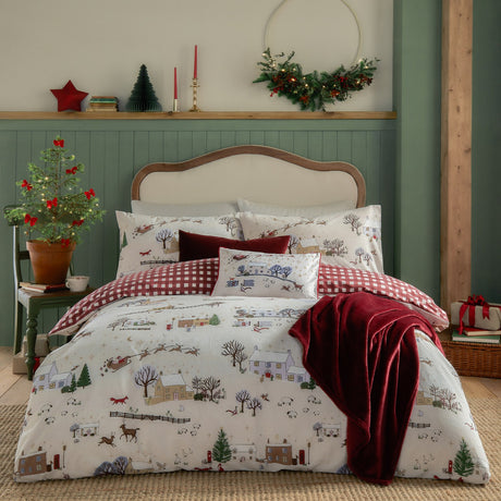 Cotswoldchristmas Gingham Duvet Cover Set in cream and burgundy on a bed, featuring a printed winter village scene reverse to a red and cream gingham check, styled in a festive bedroom.