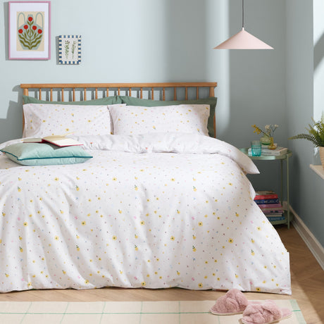 Cottage Garden Reversible Ditsy Duvet Cover Set in white with scattered multicoloured floral print, styled on a bed with matching pillowcases in a pastel green bedroom.