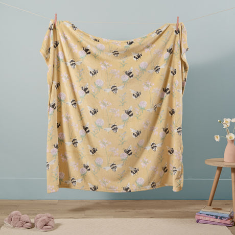 Country Bee Animal Polyester Throw in honey yellow with bumblebee and clover print, draped on a clothesline against a pale blue wall.