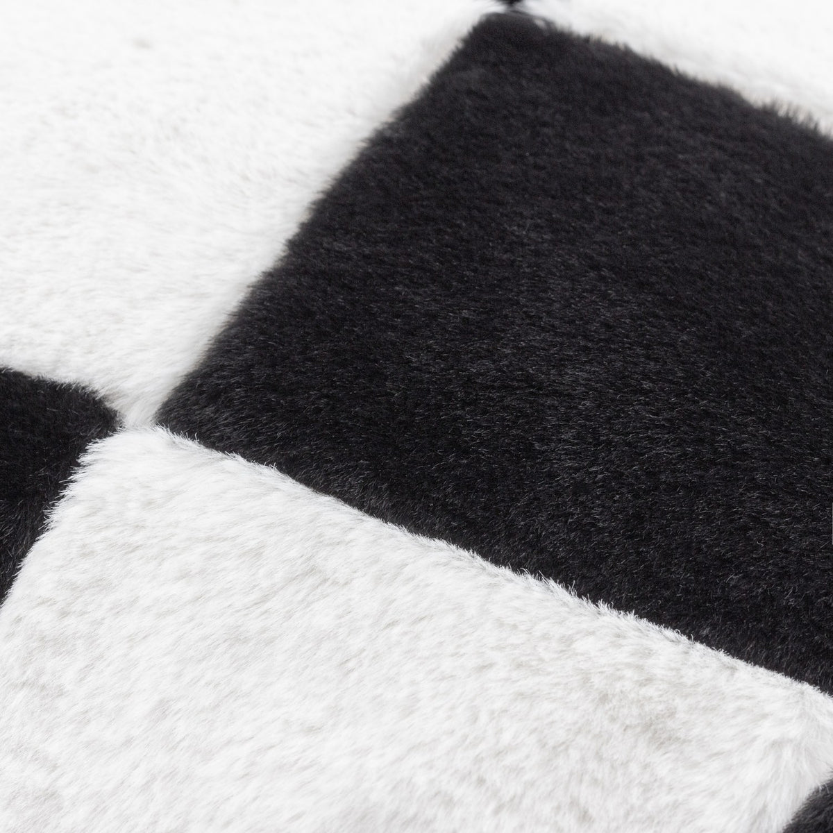 Close-up of the Cozee Check Plain Faux Fur Cushion in black and white, showing the soft faux fur pile in an oversized checkerboard pattern.