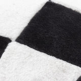 Close-up of the Cozee Check Plain Faux Fur Cushion in black and white, showing the soft faux fur pile in an oversized checkerboard pattern.