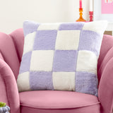 Cozee Check faux fur cushion in lilac and white checkerboard pattern, 50 x 50cm square, shown on a pink armchair in a living room setting.