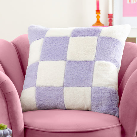 Cozee Check faux fur cushion in lilac and white checkerboard pattern, 50 x 50cm square, shown on a pink armchair in a living room setting.