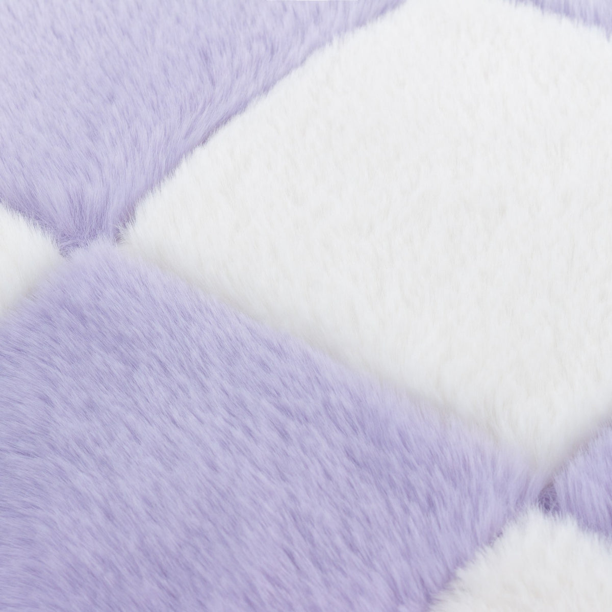 Close-up of the Cozee Check faux fur cushion in lilac and white, showing the checkerboard pattern and dense polyester pile texture.