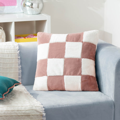 Cozee Check Plain Faux Fur Cushion in dusky pink and cream, a four-by-four checkerboard square cushion shown on a light grey sofa in a living room setting.