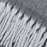 Close-up of the Cosy Plain Polyester Throw in charcoal grey, showing the woven texture and deep white tasselled fringe along the edge.