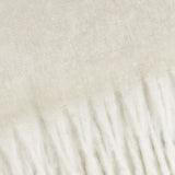 Close-up of the Cosy Plain Polyester Throw in ecru, showing the brushed woven surface transitioning into a knotted fringe edge in cream tones.