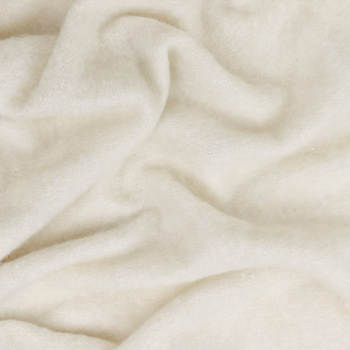 Cosy Plain Polyester Throw in ecru, shown draped in soft folds showing a brushed, hazy woven texture in warm cream tones.