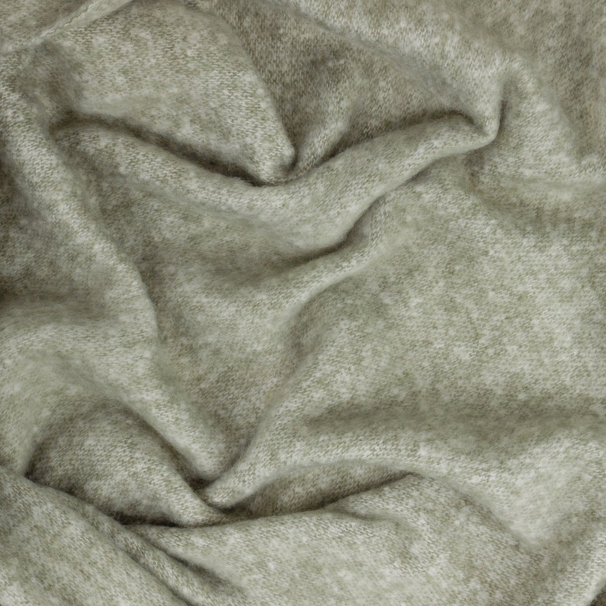 Cosy Plain Polyester Throw in sage green, shown draped and gathered to reveal its soft woven texture with subtle tonal shading.