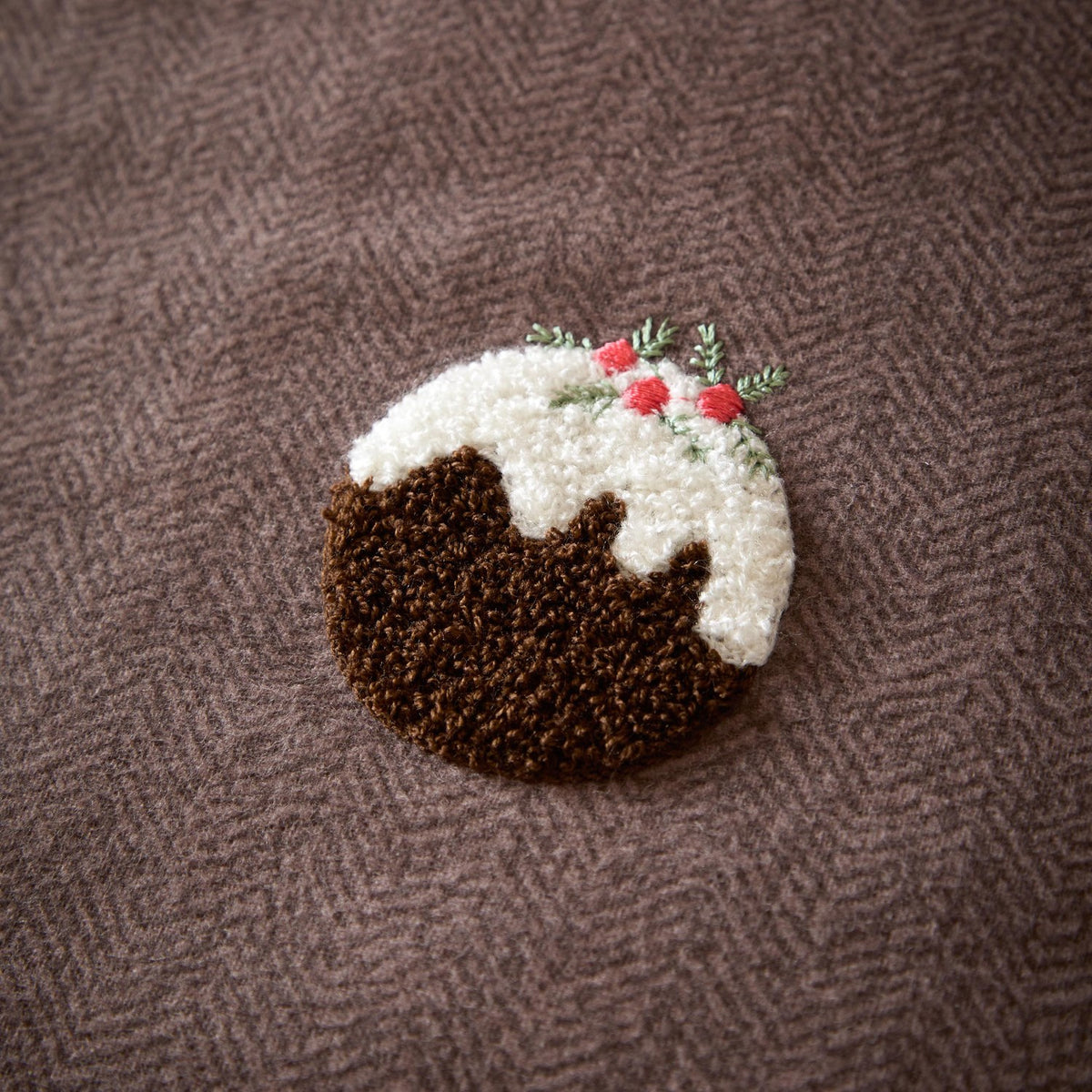 Christmas Pudding Tufted Brushed Duvet Cover Set in chocolate-brown, close-up of a raised loop-tufted pudding motif with white icing and red-green sprig detail on herringbone cotton fabric.