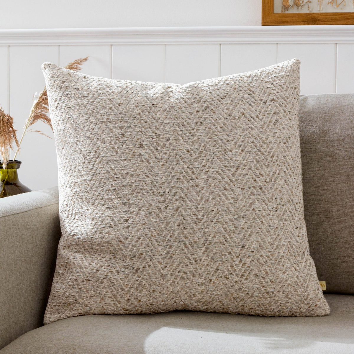 Croft Plain Velvet Cushion in natural oatmeal chevron twill, 50 x 50cm, shown on a beige sofa in a living room setting.