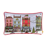 Christmas Spirit rectangular velvet cushion in multicolour, printed with a festive townhouse street scene, red piped edges, on a plain white background.