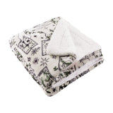 Folded Celestial Stories throw in cream with charcoal tarot card, star and moon print and green foliage detail, reverse sherpa lining visible, on a plain white background.