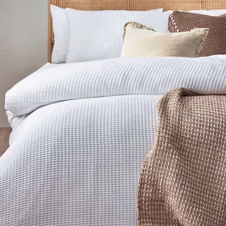 White Chunky Waffle Cotton Duvet Cover Set on a bed with matching pillowcases, styled with cream and brown cushions and a waffle-textured throw.