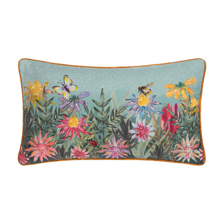 Country Wilds Blossom Meadow rectangular cushion in sky blue with rust piping, featuring a hand-painted floral meadow, butterfly, bumblebee and ladybird, shown on a plain white background.