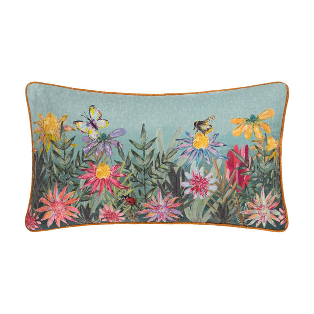 Country Wilds Blossom Meadow rectangular cushion in sky blue with rust piping, featuring a hand-painted floral meadow, butterfly, bumblebee and ladybird, shown on a plain white background.