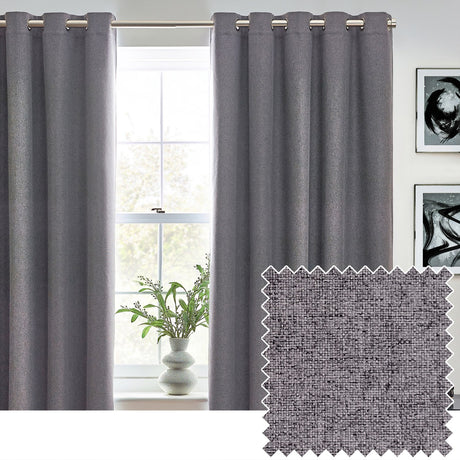 Dawn Plain Reversible Eyelet Curtains in charcoal grey hang at a bedroom window, showing metal eyelet headings on a pole, with a fabric swatch inset revealing the woven textured finish.
