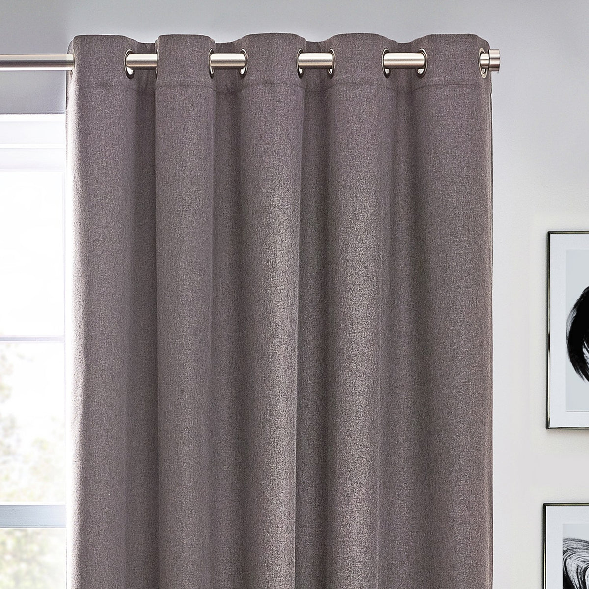 Dawn Plain Reversible Eyelet Curtains in charcoal, hanging from a brushed metal pole through silver eyelets, showing textured fabric folds in a room setting.