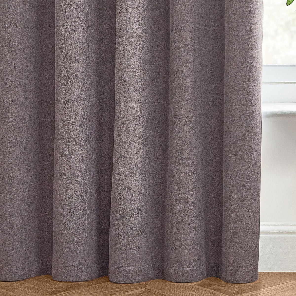 Dawn Plain Reversible Eyelet Curtains in charcoal, showing soft-textured fabric folds with a subtle marl effect, hung near a window with wooden flooring.