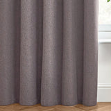Dawn Plain Reversible Eyelet Curtains in charcoal, showing soft-textured fabric folds with a subtle marl effect, hung near a window with wooden flooring.
