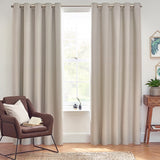 Dawn Linen Reversible Eyelet Curtains in natural linen hang either side of a window in a living room, shown with eyelet header, brass pole, and rings above a wooden floor.