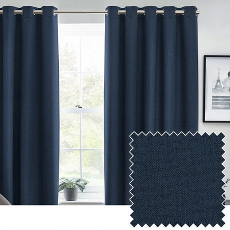 Dawn Plain Lined Eyelet Curtains in midnight blue, hung on a silver pole beside a window in a living room, with a fabric swatch showing the textured polyester weave.