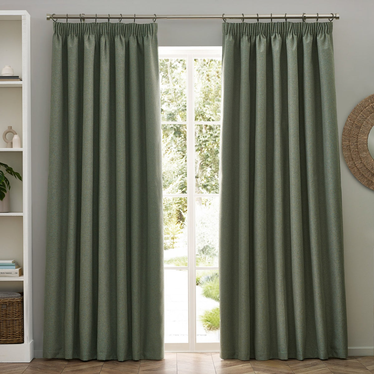 Dawn pencil pleat curtains in eucalyptus green marl-effect polyester, shown pleated on a pole beside a glazed door in a living room.