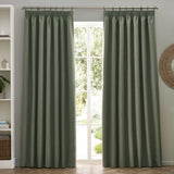 Dawn pencil pleat curtains in eucalyptus green marl-effect polyester, shown pleated on a pole beside a glazed door in a living room.