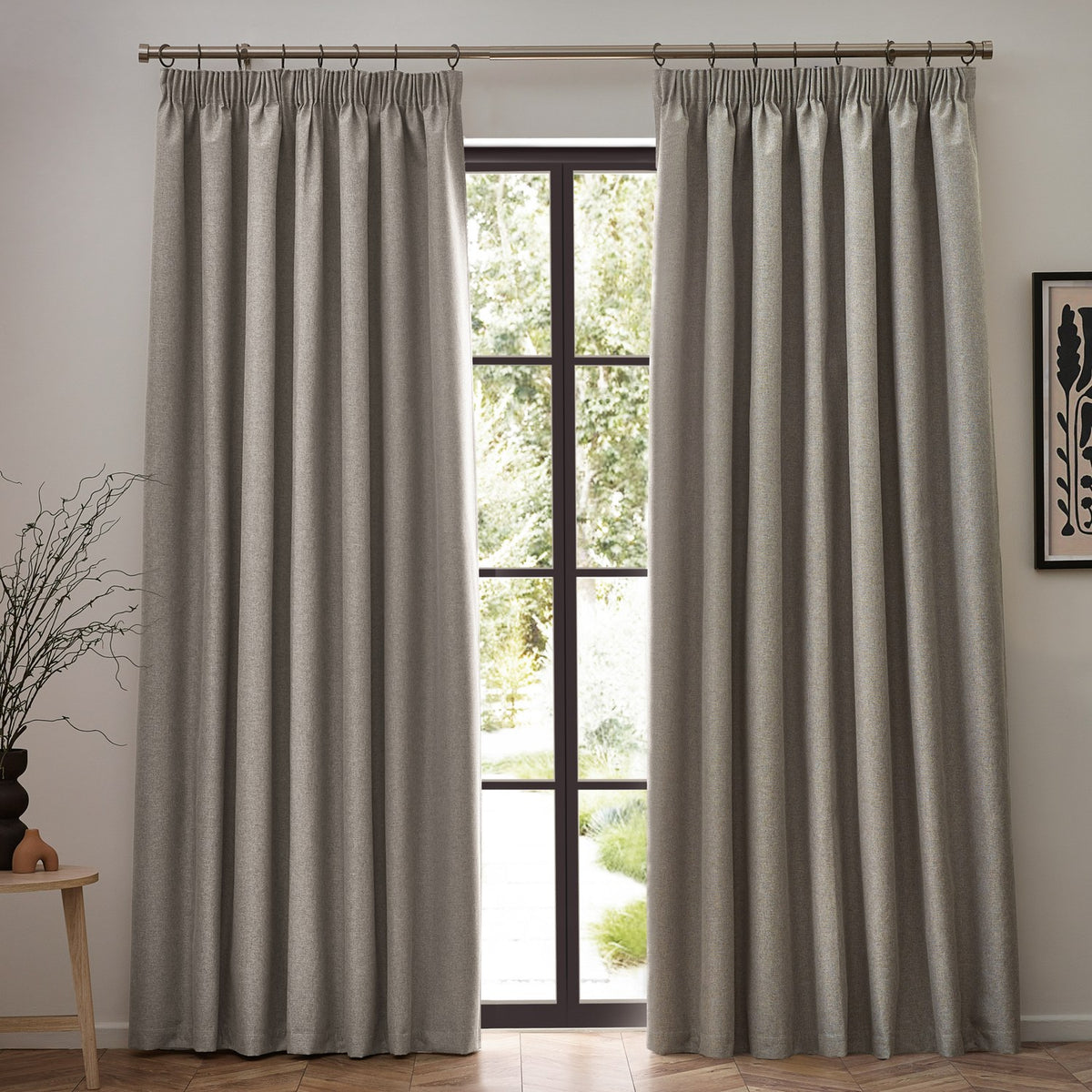 Dawn pencil pleat curtains in linen, pair of full-length beige woven curtains with pencil pleat heading hung either side of a black-framed window in a living room.