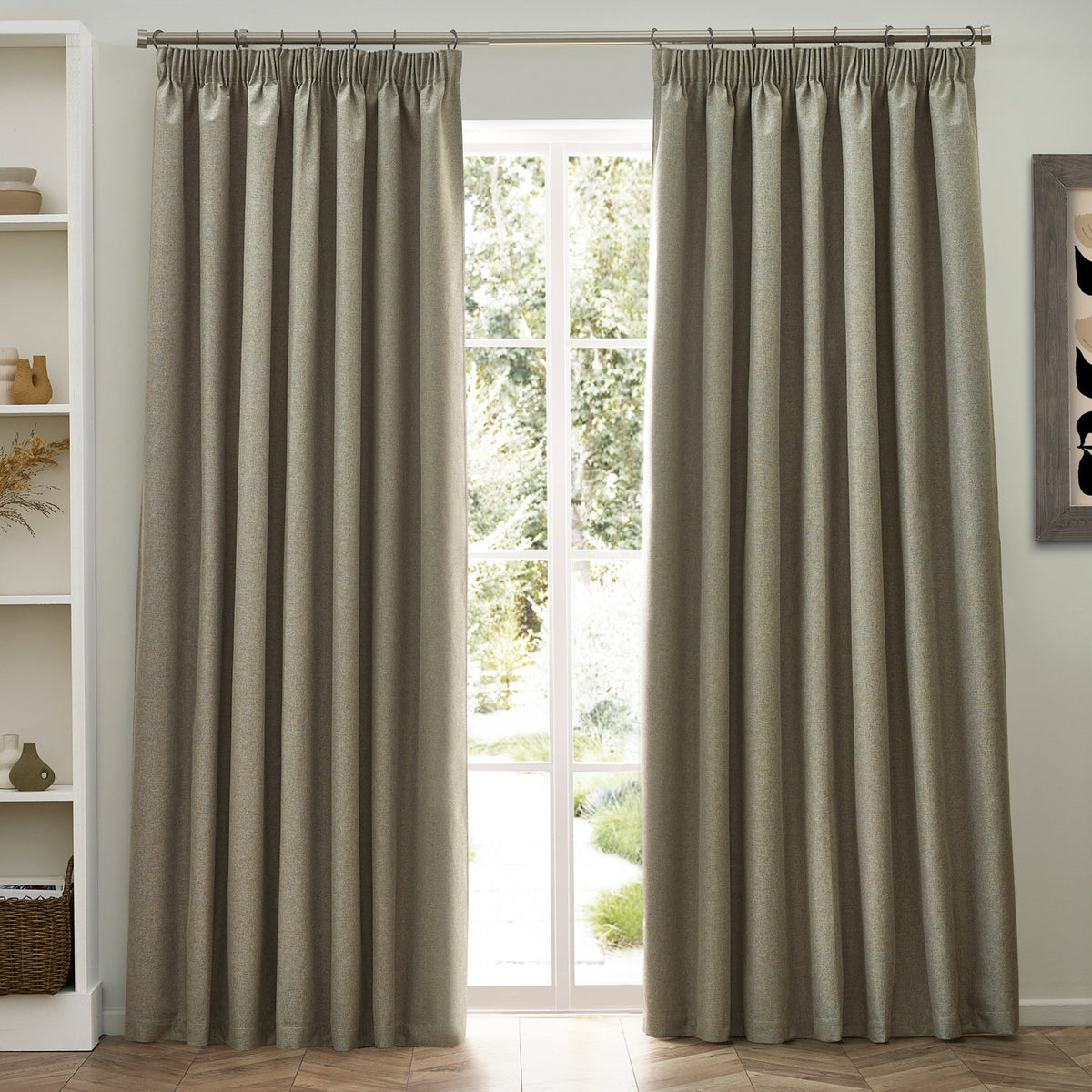 Dawn pencil pleat curtains in natural marl-effect polyester, hung either side of a French door in a living room with white shelving and wooden flooring.