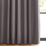 Dawn pencil pleat curtains in charcoal grey, close-up of pleated polyester fabric with a marl-effect texture, hung by a window with wooden flooring.