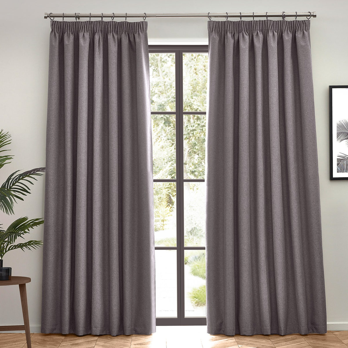 Dawn pencil pleat curtains in charcoal grey, pair of pencil-pleat panels in textured polyester hung on a rod beside a glass door in a living room.