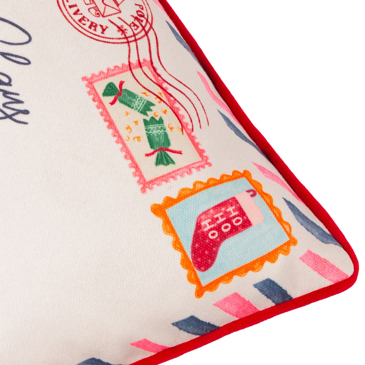 Close-up of the Dear Santa Velvet Cotton Cushion corner, showing cream fabric with printed stamps, red piping edge, and diagonal airmail-style stripes in pink and navy.