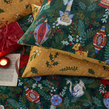 Deck The Halls polycotton duvet cover set in pine green, printed with baubles, holly, a cherub, deer and swan, paired with a mustard-gold reverse pillowcase.