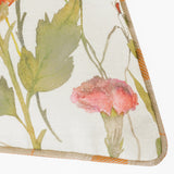 Close-up of the Delamere Reversible Linen Cushion in Russet, showing a hand-painted wildflower print with pink dahlia and green leaves on cream linen, edged with orange and sand check piping.