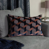 Delano Jacquard Velvet Cushion in blush, navy and charcoal, showing a woven geometric lattice pattern, styled on a grey sofa with a navy throw nearby.