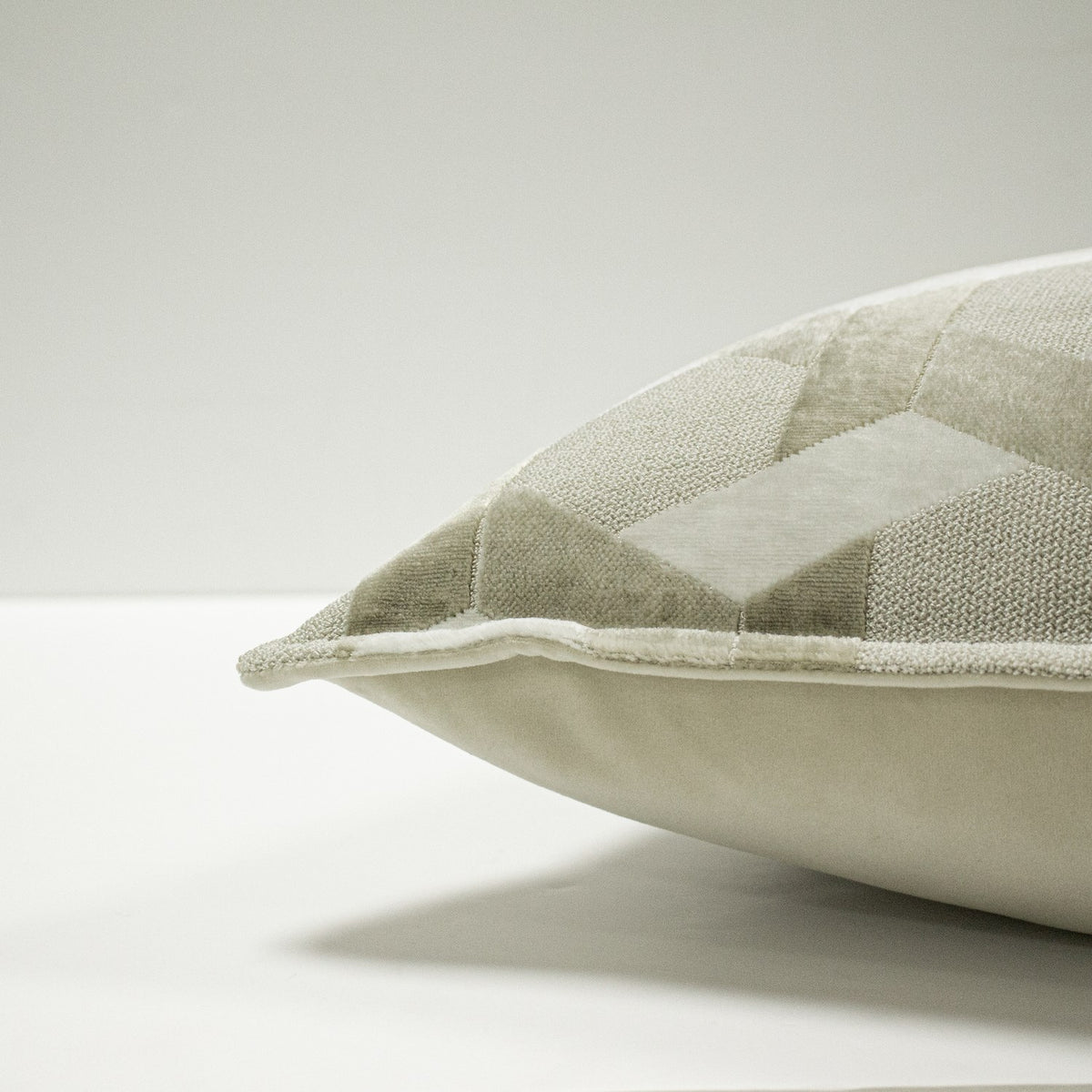 Close-up of the Delano Jacquard Velvet Cushion in ivory/taupe, showing the raised lattice pattern with velvet and woven facets and a corner piped edge, on a plain white background.