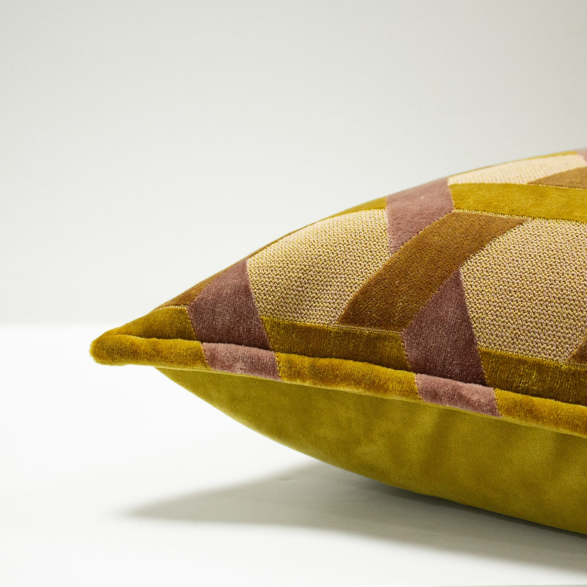 Delano Jacquard Velvet Cushion in ochre and blush, showing a geometric lattice pattern with velvet piped edge, corner close-up on a plain light background.