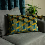 Delano Jacquard Velvet Cushion in teal, gold and green with an interlocking lattice pattern, styled on a grey sofa near a teal curtain and plant.
