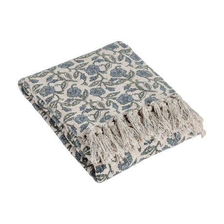 Delphine Floral Cotton Throw in Delph Blue, folded with fringed edge showing a dusty blue and green floral print on cream cotton, shown on a plain white background.