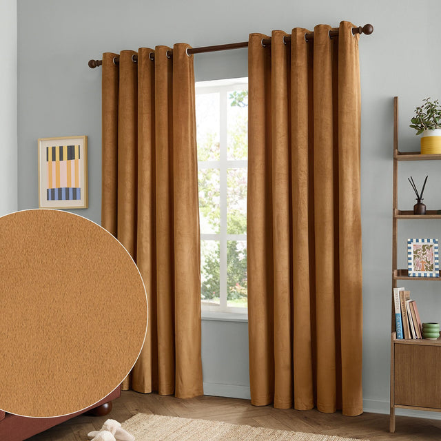 Caramel velvet eyelet curtains with brown grommet rings hanging full-length either side of a window in a light grey living room, inset swatch showing the plain matte pile texture.