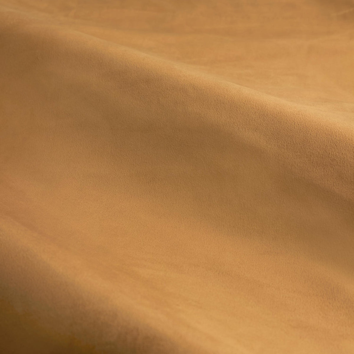 Close-up of caramel gold velvet fabric from The Ultimate Velvet Plain Fully Lined Eyelet Curtains, showing soft matte pile with gentle folds and light-catching sheen.
