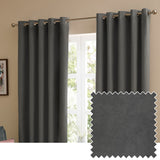 Charcoal grey velvet eyelet curtains with matt finish hung on a metal pole in a living room window, shown with a fabric swatch of the same colour.