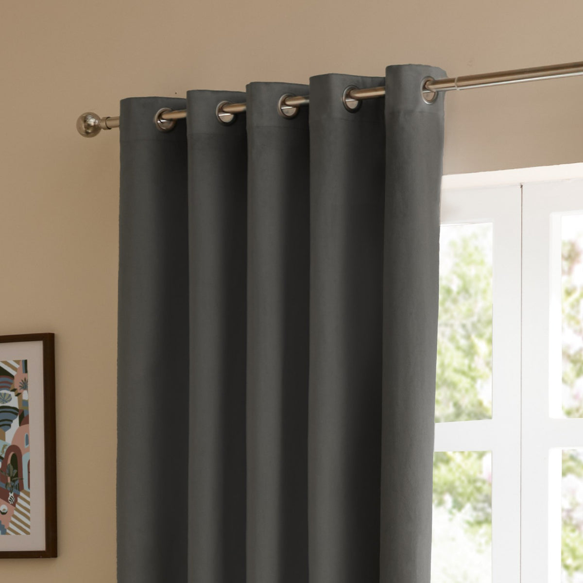 Charcoal velvet eyelet curtains with brushed metal grommets hung on a chrome pole beside a window in a living room setting.