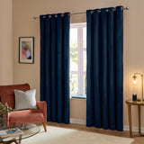 The Ultimate Velvet Plain Lined Eyelet Curtains in royal blue, matt velvet finish with eyelet header on a pole, shown in a living room beside a window.