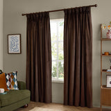 Chocolate brown velvet pencil pleat curtains with pinch-pleat heading on a wooden pole, shown framing a window in a living room with a green sofa and ladder shelf.