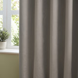 Silver-grey velvet pencil pleat curtains in soft folds beside a white-framed window with a potted plant on the sill.