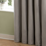 Silver-grey velvet pencil pleat curtains in soft matte polyester hanging in deep folds beside a window with green walls and wooden flooring.