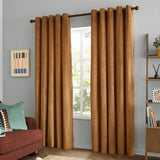 Caramel gold velvet eyelet curtains with grommet top hanging on a dark rod either side of a window, shown in a living room with a rust sofa and light grey wall.